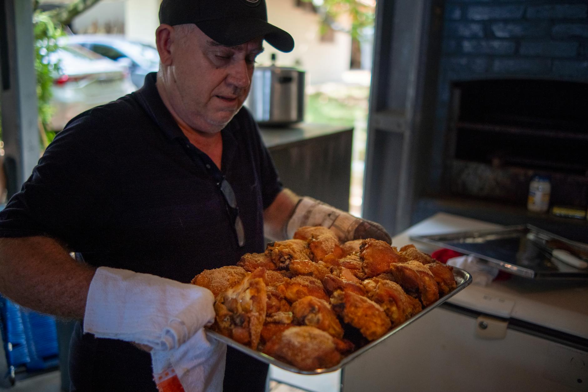 Mężczyzna trzyma tacę z pieczonym kurczakiem w rustykalnej kuchni